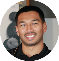 A man with short hair is smiling, wearing a black shirt. The image is circular.